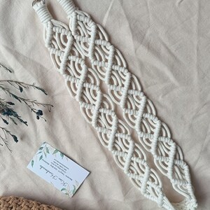 May include: White macrame bag strap with silver clasps. The strap is made of cotton cord and has a diamond pattern.