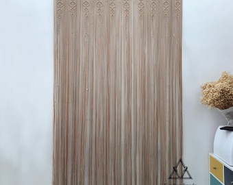 May include: A beige macrame curtain with a geometric pattern. The curtain is made of natural fibers and has a rustic, bohemian style.