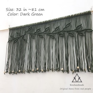 May include: Dark green macrame wall hanging with a leaf design and wooden beads. The hanging measures 32 inches or 81 centimeters in length.