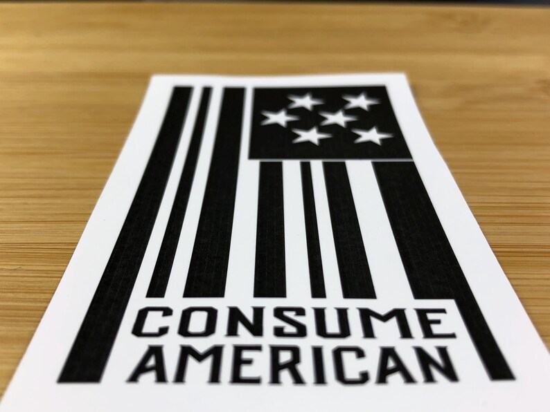 May include: Black and white sticker with a stylised American flag design and the text "CONSUME AMERICAN".