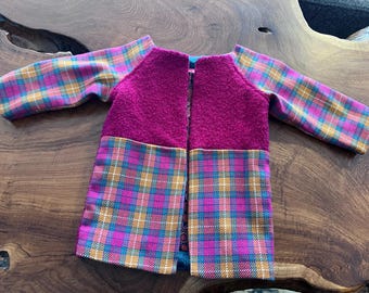 May include: A pink and brown plaid jacket with a magenta fleece bodice. The jacket has a zipper closure and long sleeves.