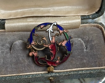 May include: A vintage enamel and gold brooch in the shape of a stylized letter 'G' with blue, green, white, and pink enamel. The brooch is in a velvet-lined box with the inscription "Gowing Bros. Ltd Sydney".