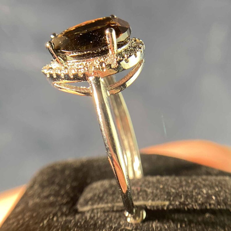 May include: A silver ring with a pear-shaped brown gemstone surrounded by a halo of smaller clear gemstones.