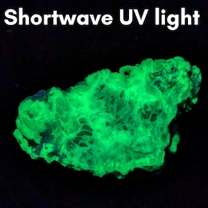 May include: A glowing green rock formation under a black background. The text "Shortwave UV light" is at the top of the image. The rock has a textured surface and appears to be illuminated.