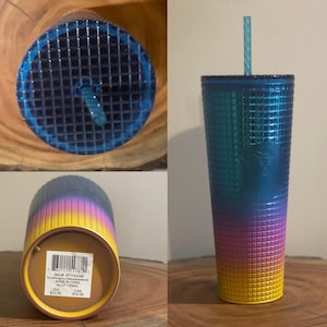 May include: A stainless steel tumbler with a gradient design featuring blue, purple, pink, and yellow colors. The tumbler has a textured, grid-like pattern and a clear plastic lid. The tumbler is 24 oz and has a SKU of 011143246. The text "The Starbucks  Stainless Steel Tumbler" is printed on the bottom of the tumbler.