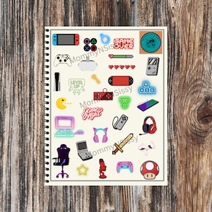 May include: A sheet of colorful stickers featuring various gaming-themed icons, including a game controller, a headset, a sword, a keyboard, a Pac-Man, a level up sign, a game over sign, and a game night sign.
