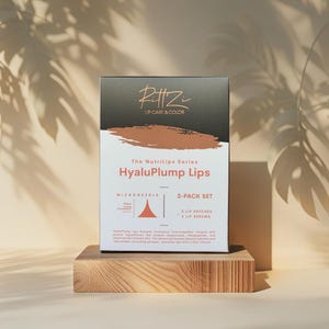 May include: A product box for "HyaluPlump Lips" lip care, featuring the brand name "PittZ" and product details. The box is white with black and brown accents, and sits on a wooden display. The text includes "2-PACK SET" and "2 LIP PATCHES, 2 LIP SERUMS".