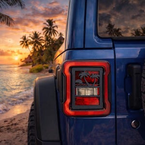 Puede incluir: Parte trasera de un Jeep azul con una luz trasera con borde rojo que presenta una silueta de palmera. El fondo muestra una escena de playa tropical con una puesta de sol sobre el océano. Una rueda de repuesto está montada en la parte trasera.