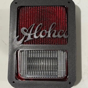 May include: A black plastic frame with a red lens and a white lens. The red lens has the word "Aloha" written in gray on it.