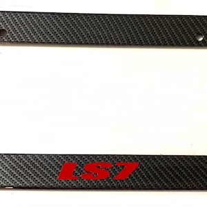May include: Black carbon fiber license plate frame with a red "LS7" logo.