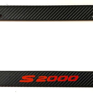 May include: Black carbon fiber license plate frame with red "S2000" lettering.
