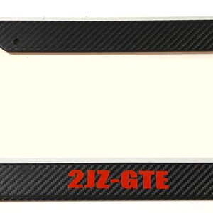 Pode incluir: Moldura de placa de fibra de carbono preta com inscrição vermelha "2JZ-GTE".