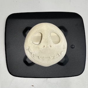 May include: A white 3D printed Jack Skellington face on a black background.