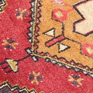 May include: Close-up of a red, orange, and black patterned rug with a geometric design. The rug has a soft, fuzzy texture.