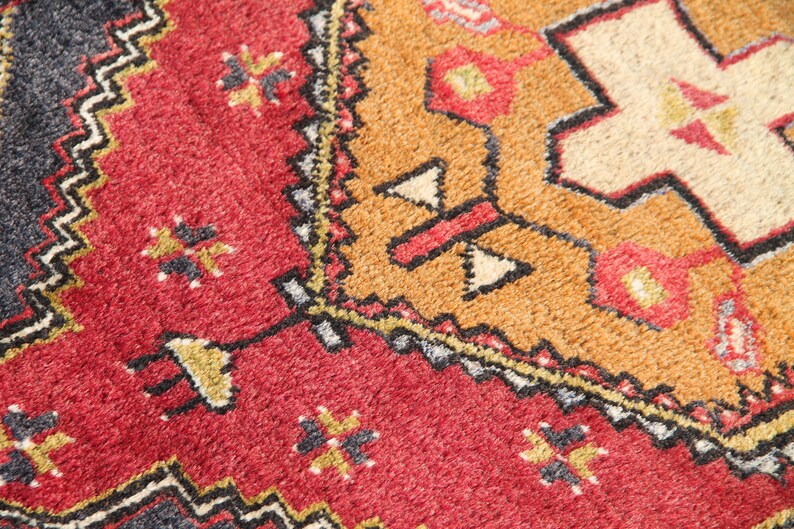May include: Close-up of a red, orange, and black patterned rug with a geometric design. The rug has a soft, fuzzy texture.