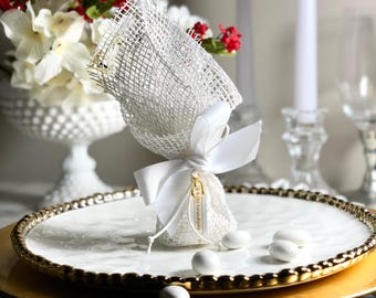 May include: White favor bag with a white bow and a gold tag that says "A thousand thanks". The bag is filled with white Jordan almonds and is sitting on a white and gold plate.