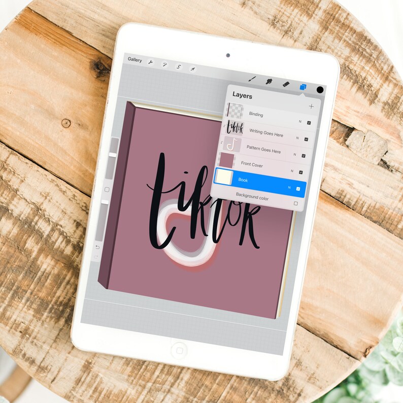 Może przedstawiać: Cyfrowa ilustracja projektu okładki książki na tablecie. Okładka ma stonowany kolor malinowy z napisem "tiktok" w stylizowanej czcionce. Ekran tabletu wyświetla warstwy oprogramowania do projektowania.