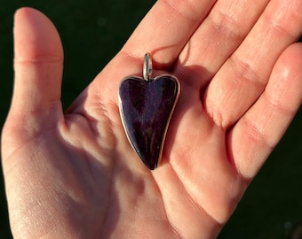 May include: A heart-shaped pendant made of dark purple stone with silver accents.