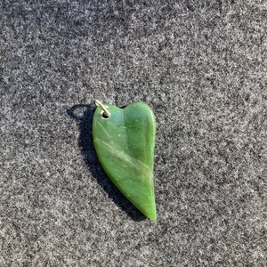 May include: A green heart-shaped jade pendant with a silver bail.