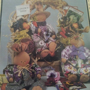 May include: A collection of handmade bunny dolls with floral and plaid patterned clothing. One bunny wears a straw hat and holds a carrot. The dolls are surrounded by decorative elements, including a wreath and seed packets. The text "Garden Patch" is visible.