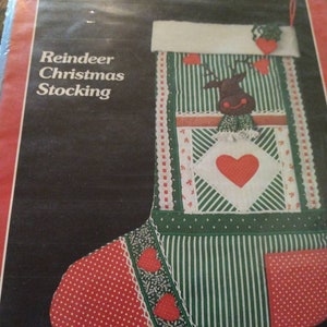 May include: A vintage Christmas stocking sewing pattern featuring a reindeer design. The pattern includes a green and white striped fabric, red polka dot fabric, and a white fabric with red hearts. The pattern is titled "Reindeer Christmas Stocking" and is from "Yours Truly" patterns.