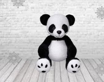 May include: A crocheted panda bear plush toy with black and white fur. The panda is sitting with its paws in front of it.
