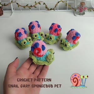 May include: Crochet snail toys in various colors. Each snail has a pink and blue shell, a green body, and a blue and turquoise base. The text "CROCHET PATTERN SNAIL GARY SPONGEBOB PET" is visible.