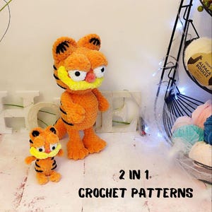 May include: Two crocheted Garfield plush toys, one large and one small, both orange with black stripes and yellow eyes. The text "2 IN 1. CROCHET PATTERNS" is below the toys.