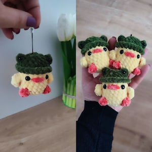 Op de afbeelding: Drie gele gehaakte eendjes met groene gehaakte hoedjes. De knuffels worden in een hand vastgehouden.