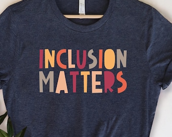 May include: A navy blue t-shirt with the text "INCLUSION MATTERS" in colorful block letters. The letters are in shades of red, orange, yellow, and gray.