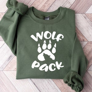 May include: A green sweatshirt with a white wolf paw print and the text "Wolf Pack" printed on the front.