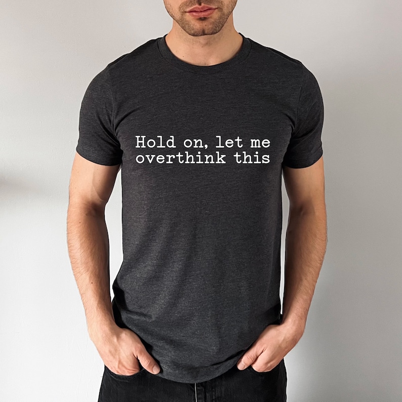 May include: A dark grey t-shirt with the text "Hold on, let me overthink this" printed in white.