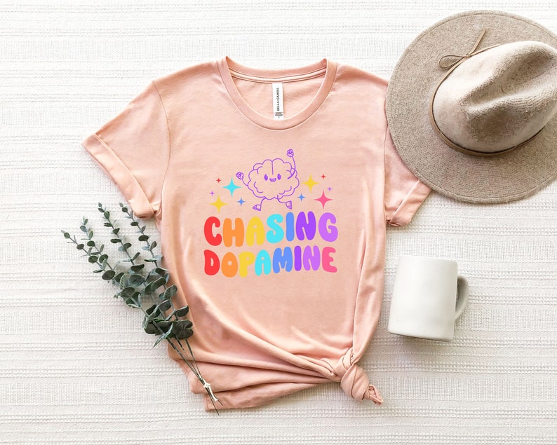 May include: A pink t-shirt with a rainbow graphic of a brain with the text "Chasing Dopamine".
