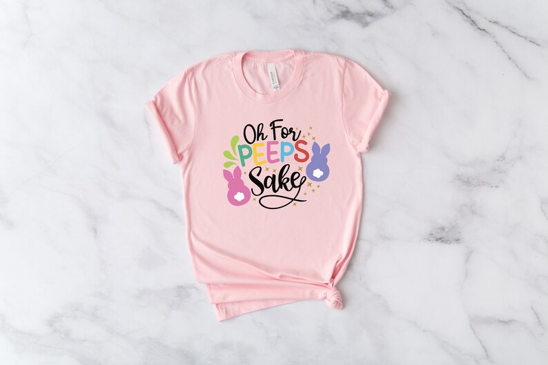 May include: Pink t-shirt with a graphic that says "Oh For Peeps Sake" with colorful bunny illustrations.