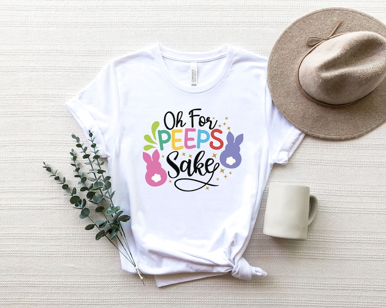 May include: White t-shirt with the text "Oh For Peeps Sake" in colorful letters and a cartoon bunny graphic.