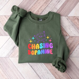 May include: A green sweatshirt with a rainbow graphic of a brain with the text "Chasing Dopamine".