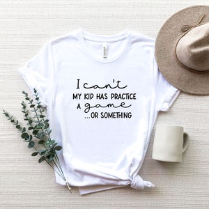 May include: White t-shirt with black text that reads "I can't my kid has practice a game...or something"