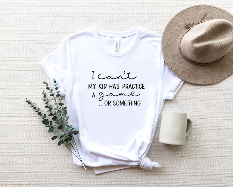 May include: White t-shirt with black text that reads "I can't my kid has practice a game...or something"