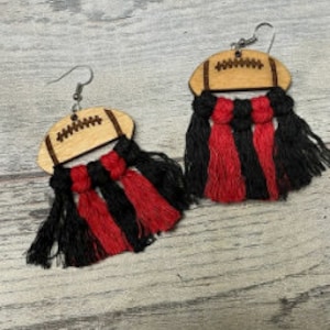 May include: A pair of wooden football-shaped earrings with red and black fringe tassels.