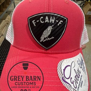May include: A red and white trucker hat with a black and silver patch that reads "F-CAW-F" with a bird illustration. The hat has the text "Grey Barn Customs" and "Evolve Elude" on it.