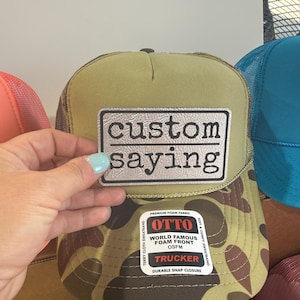 May include: A handmade wooden sign with the text "Welcome" in a playful font. The sign is painted white with a distressed finish, and features a decorative floral design in shades of pink and green. It measures approximately 12 inches wide.