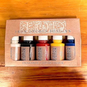 May include: A set of six 2 oz bottles of erasable liquid chalk in white, black, tomato, turmeric, and blue. The bottles are labeled with the brand name "Iron Orchid Designs".