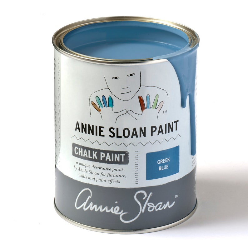 May include: A can of Annie Sloan Chalk Paint in the color Greek Blue. The can features a hand-painted illustration of a person with colorful fingertips. The text on the can reads "Annie Sloan Chalk Paint" and "Greek Blue".
