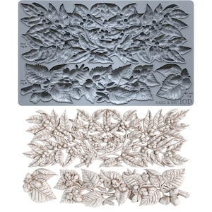 May include: A gray silicone mold featuring intricate botanical designs of leaves, berries, and nuts, paired with a white cast showing the finished relief. The mold includes text labels indicating capacities of 52ml, 38ml, and 7.4ml, plus Hazel & Bay IOD.