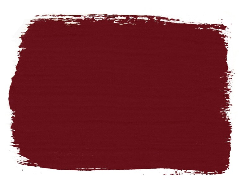 May include: A solid, dark red paint swatch with a rough, textured surface. The paint is applied with a brush stroke, creating a slightly uneven edge.