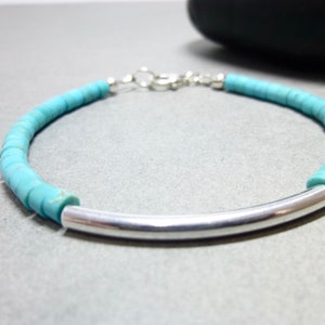 This is a simple bracelet with small disks of Kingman Turquoise. In the middle is a curved sterling silver tube that adds contrast to this unisex bracelet. It closes with a sterling silver lobster claw clasp.