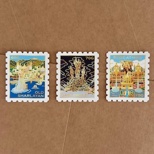Puede incluir: Tres sellos postales decorativos con ilustraciones de castillos de fantasía. Los sellos son blancos con detalles dorados y azules. El primer sello dice "Old Sharlayan" y "60G". El segundo sello dice "Garlemald" y "70G". El tercer sello dice "Radz-at-Han" y "75G".