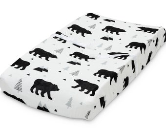 May include: A white changing pad cover with a black and gray bear and tree pattern.
