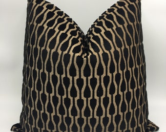 May include: Black and gold decorative pillow with a geometric pattern. The pillow is made of a soft, velvety fabric.