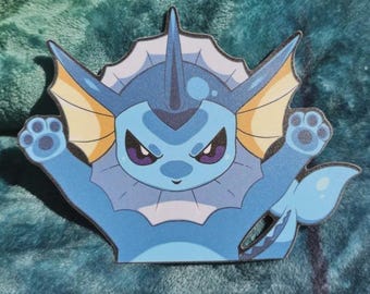 May include: A die-cut sticker featuring the blue aquatic creature Vaporeon with a large finned collar, pointed ears, and a tail. The character has dark purple eyes, a light blue body, and is depicted with both front paws raised upward.